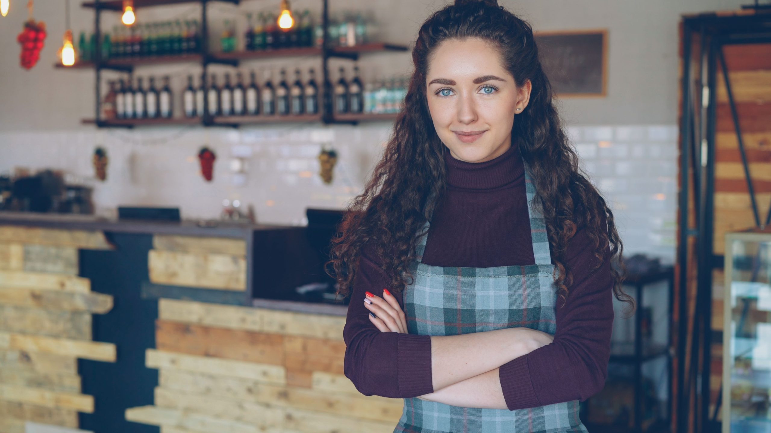 Dona de pequeno negócio sorridente à porta do seu café, representando uma PME portuguesa elegível para o Voucher Digital Portugal 2030