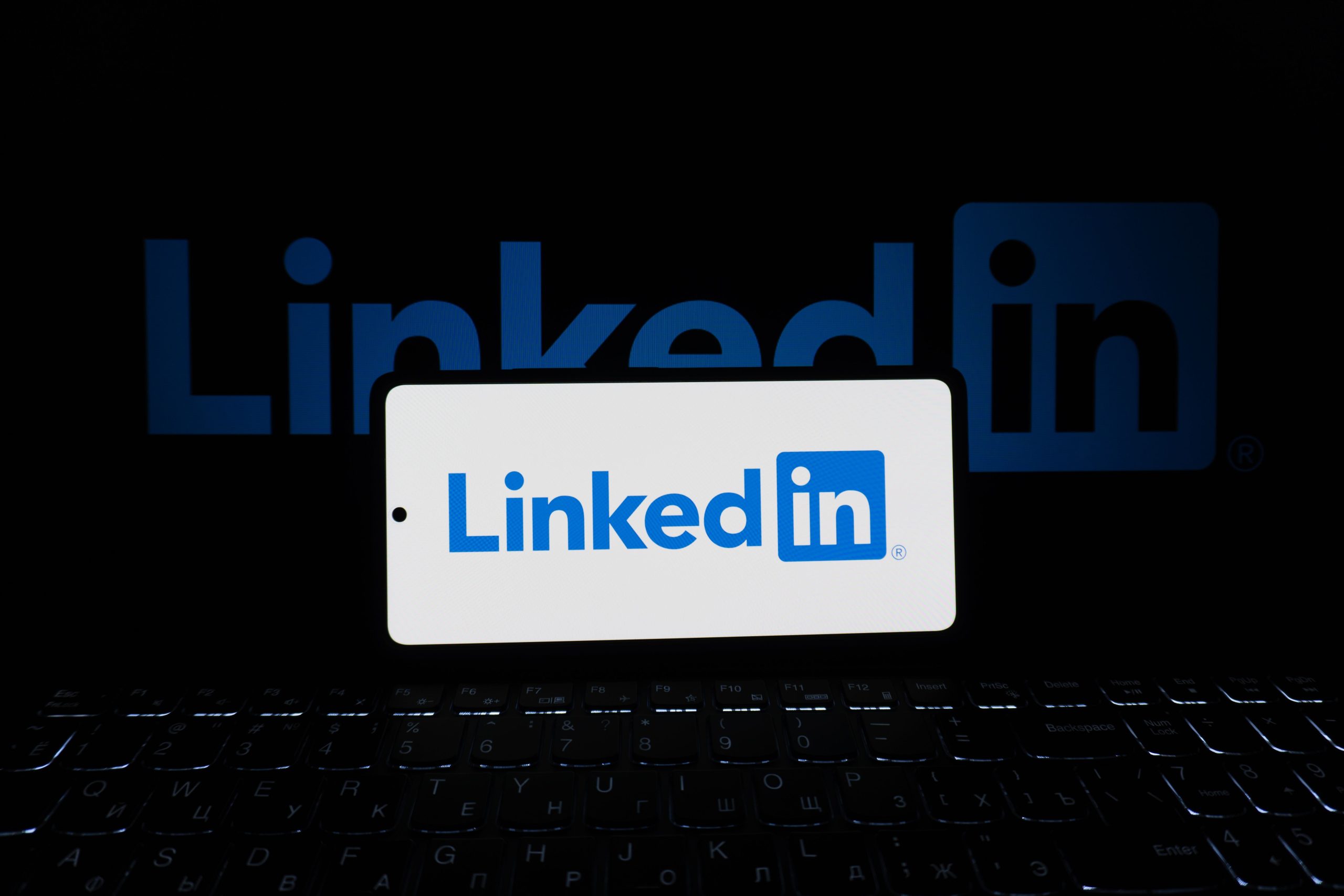 LinkedIn aberto no smartphone e no portátil, ilustrando gestão de posts com link no texto